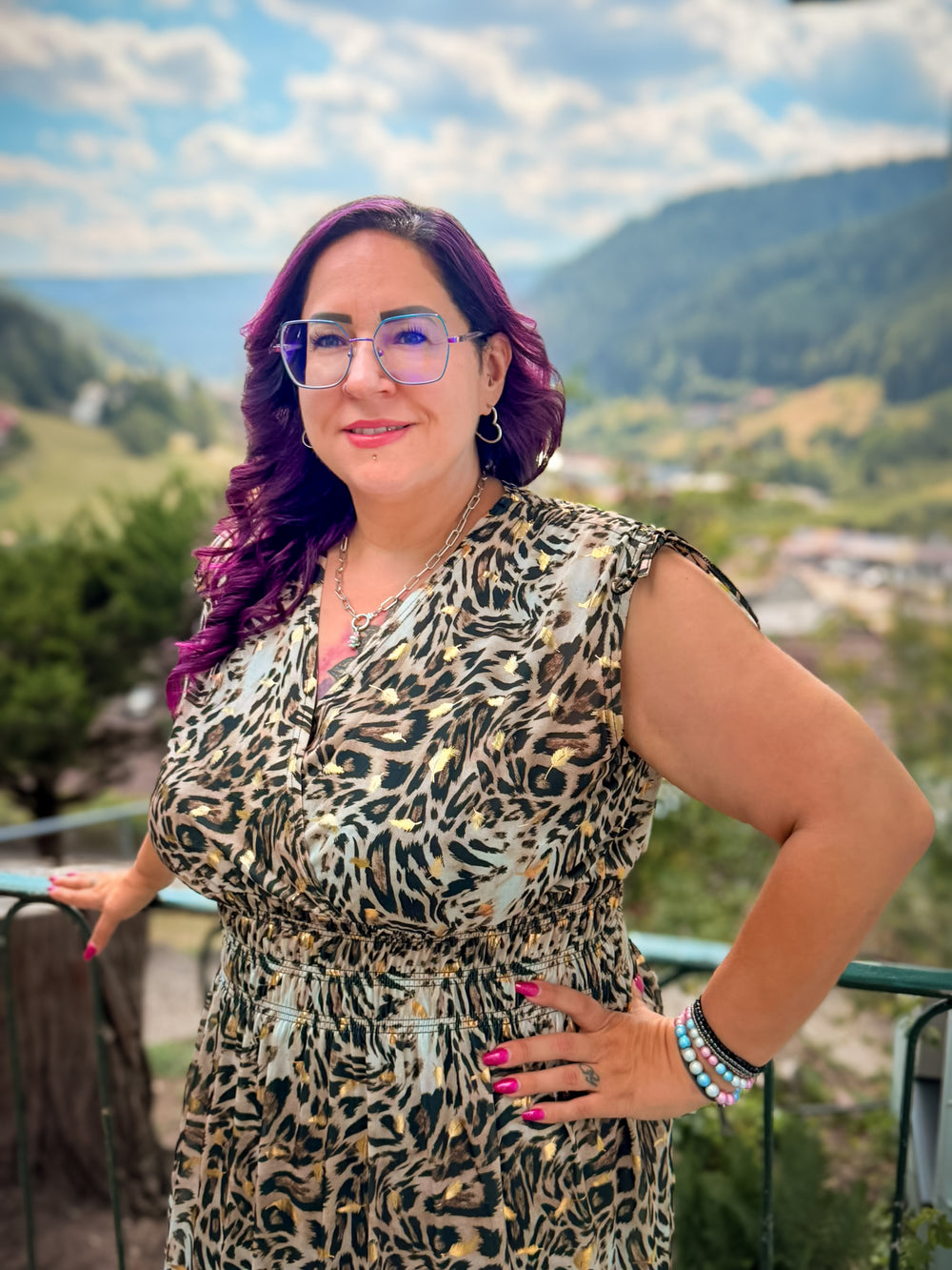 Yvonne, das Gesicht von CurvyRausch, in einem ärmellosen Kleid mit Leopardenmuster vor einem grünen Tal