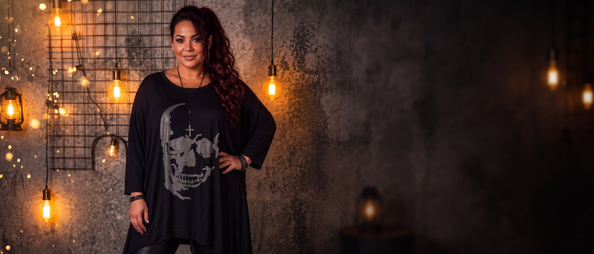Curvy Frau im schwarzen Skull Shirt mit Strass im Zipfelschnitt vor warm beleuchteter Industrial-Wand – Eröffnungsaktion bei CurvyRausch [KI]