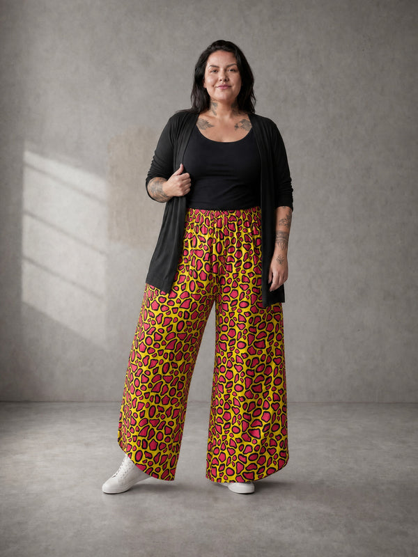 Curvy Model trägt die Pumphose Neon Leo Love in Lime mit pinkfarbenem Leo-Print zu schwarzem Top und langer schwarzer Strickjacke, dazu weiße Sneaker – in großen Größen von CurvyRausch